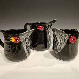 Three black ceramic pitchers with dragon head designs on the spouts, featuring red and yellow eyes.
