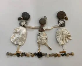 Artwork of three children holding hands, made from small pebbles, shells, and other natural materials.