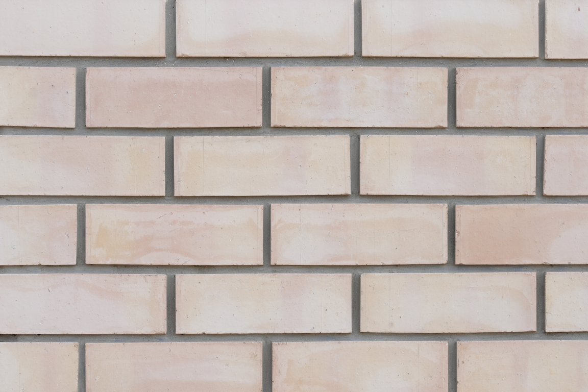 Light-colored brick wall with beige bricks and gray mortar.