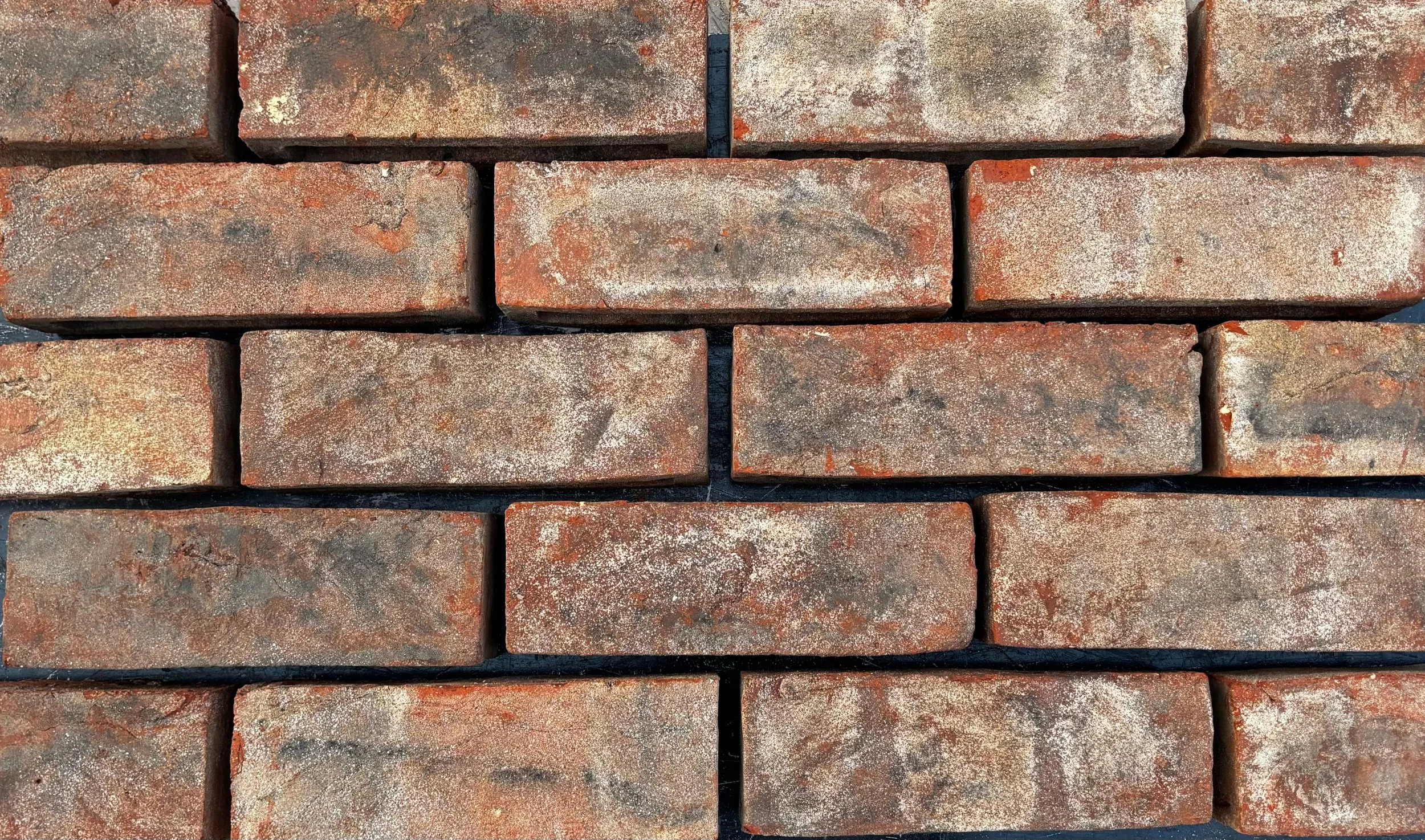 Close-up of weathered red bricks arranged in a wall.