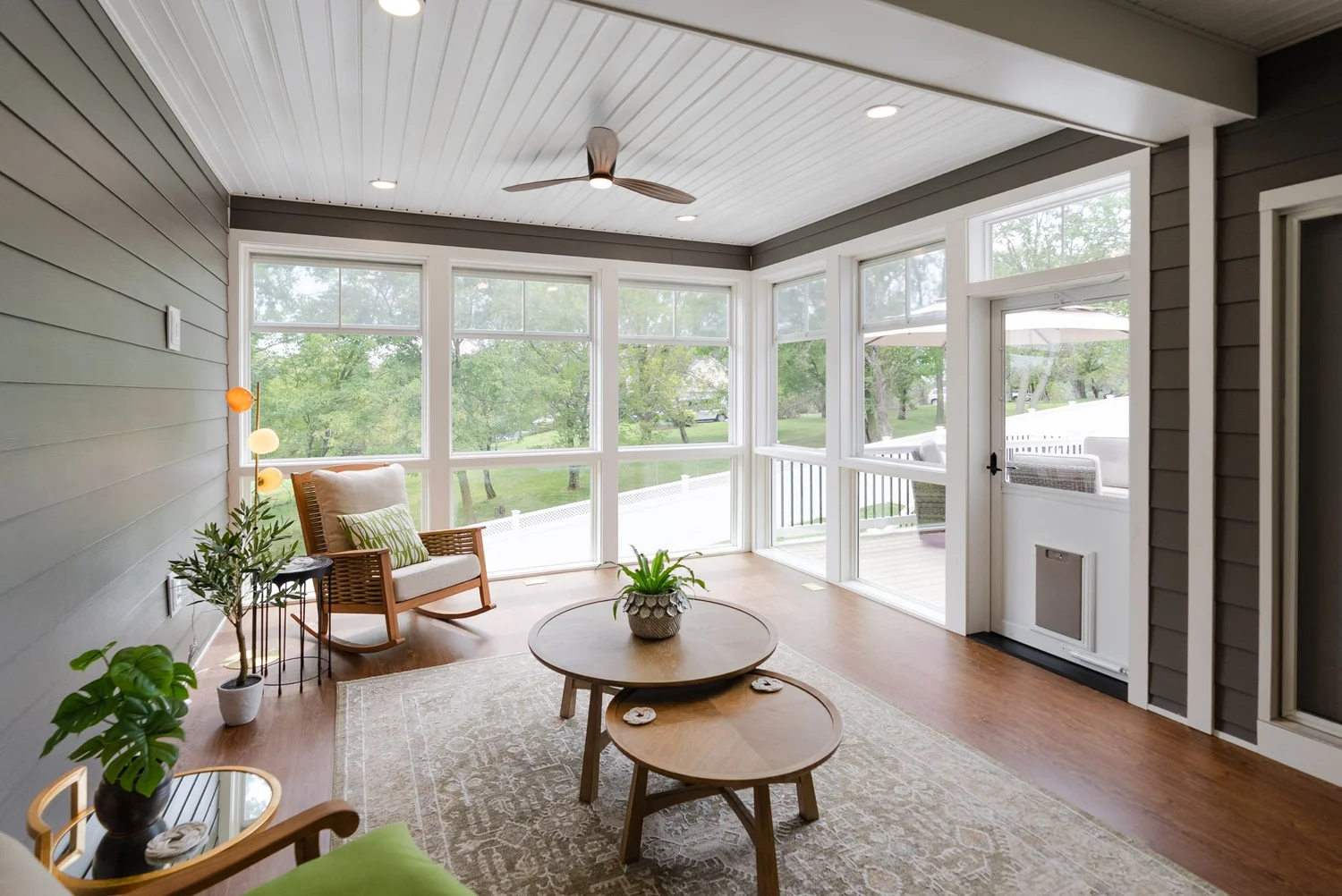 Porch interior with a ceiling fan, windows along two walls and a screen door to the deck