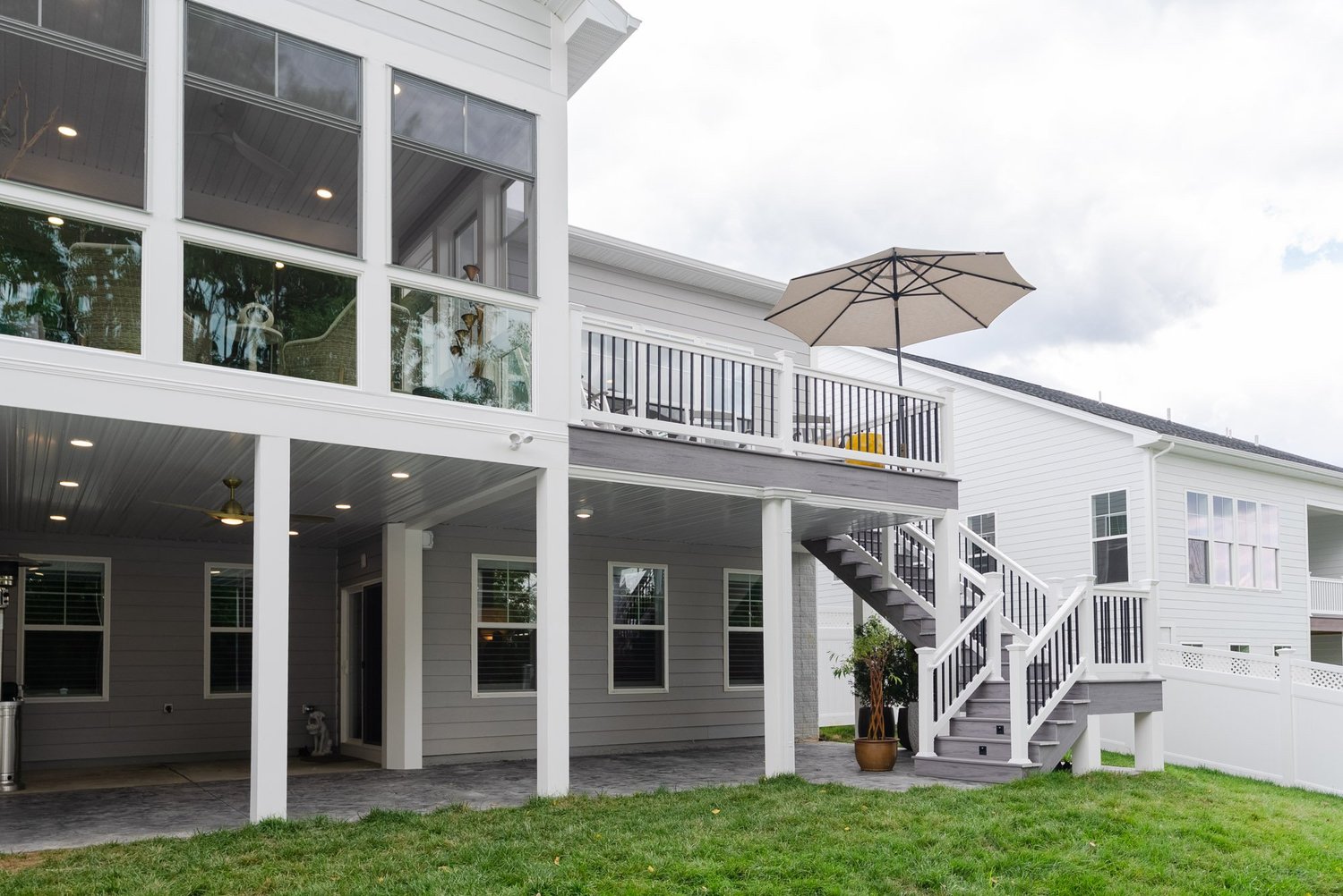 Back of the duplex with the enclosed porch above, open deck, stairway and covered patio below
