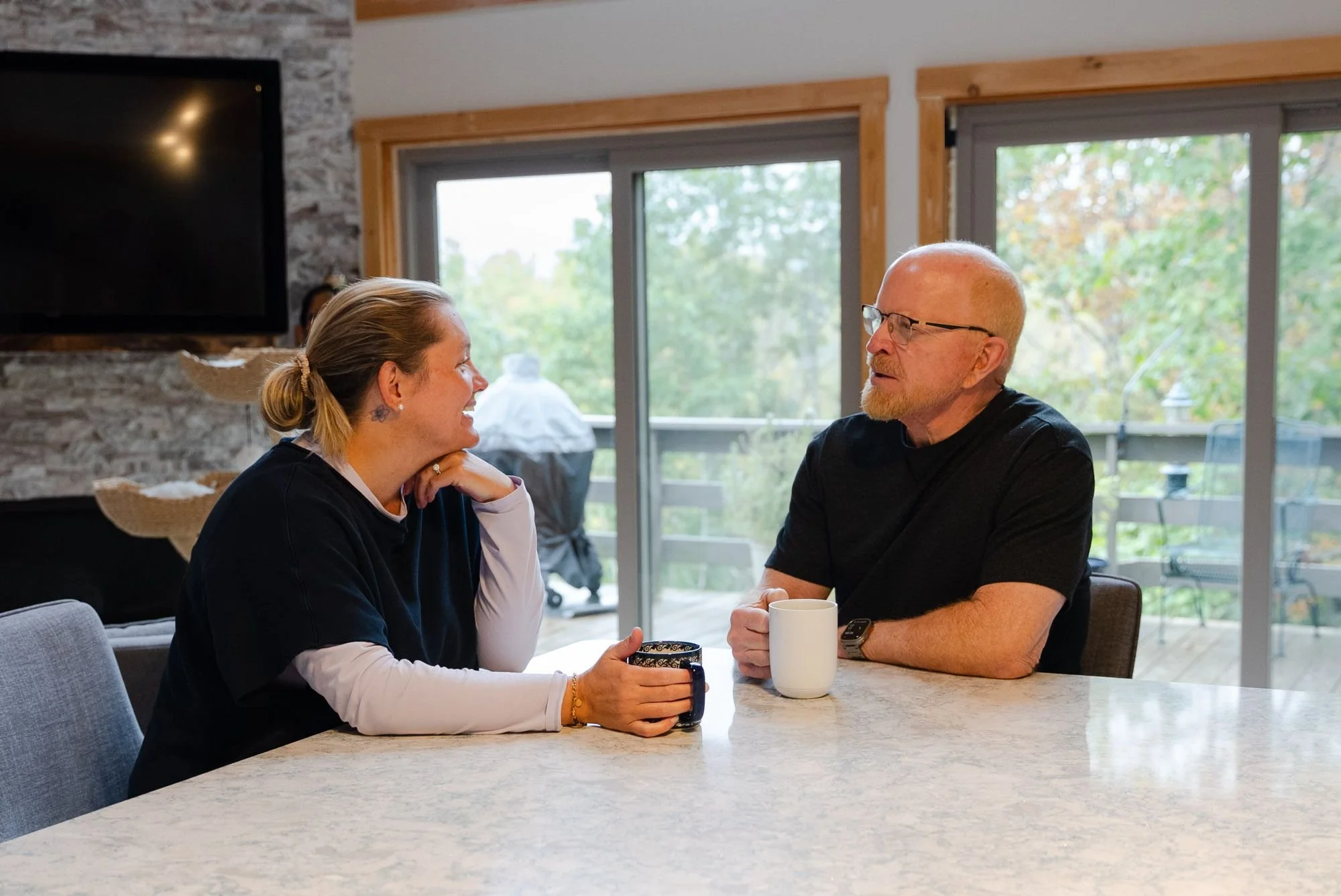 Homeowners chat over coffee at their kitchen island in front of new ProVia Endure sliding patio doors by PWD Home in Harrisonburg, VA