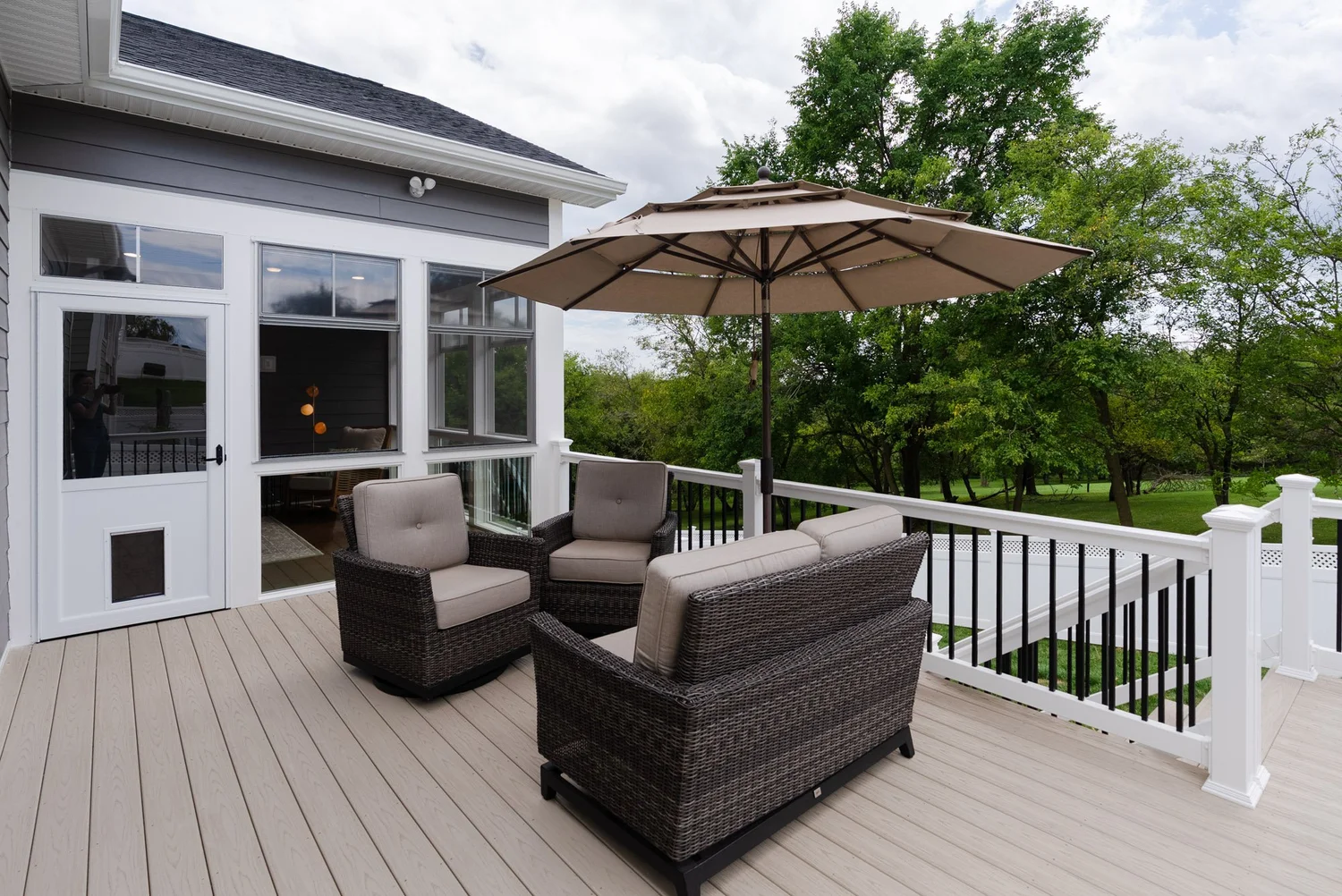 Wicker deck furniture and an umbrella on the composite deck outside the porch door