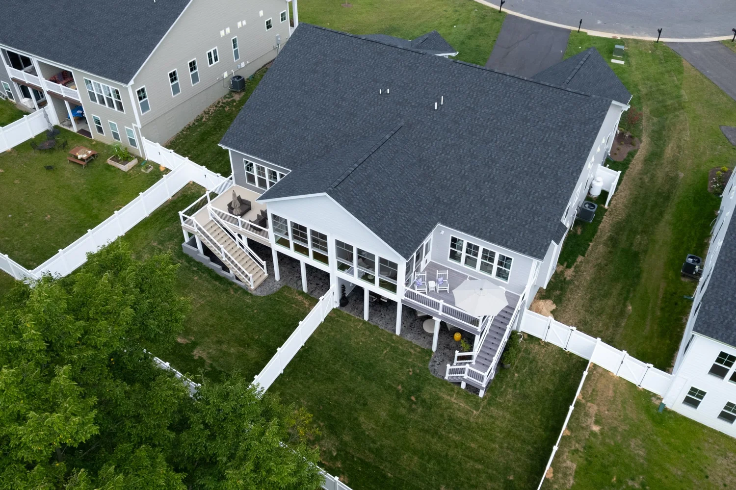 Aerial view of the home and porch addition with trees and neighboring houses around it
