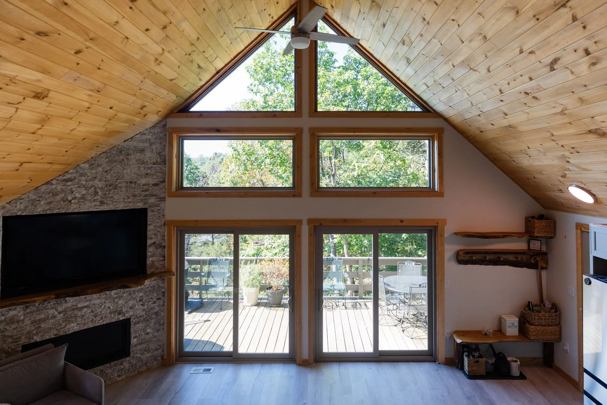 Vaulted living room with ProVia Endure replacement windows and two sliding patio doors opening to a wooded deck in the Shenandoah Valley
