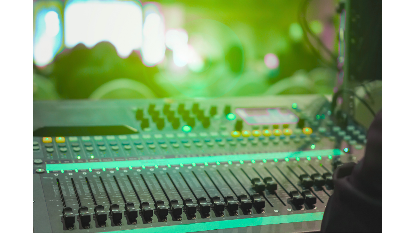 A music mixing console with numerous sliders, knobs, and lit buttons, illuminated by green lighting.