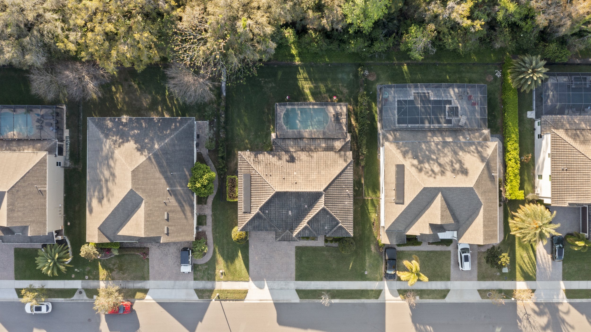 Aerial view of suburban houses with backyards and swimming pools.