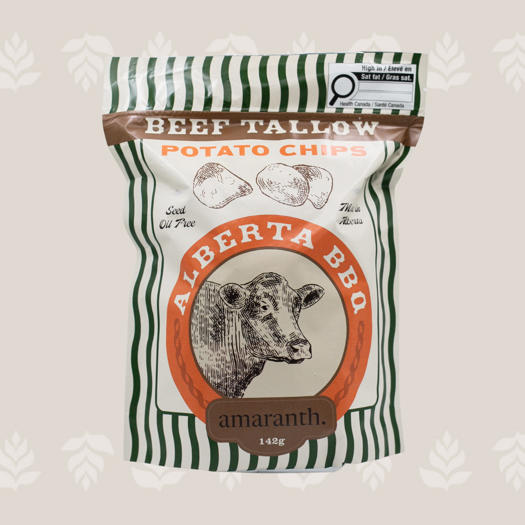 A bag of Alberta BBQ beef tallow potato chips with a drawing of a cow's head and illustrations of potatoes, featuring green and white stripe pattern and labels indicating high fat content and seed oil free.