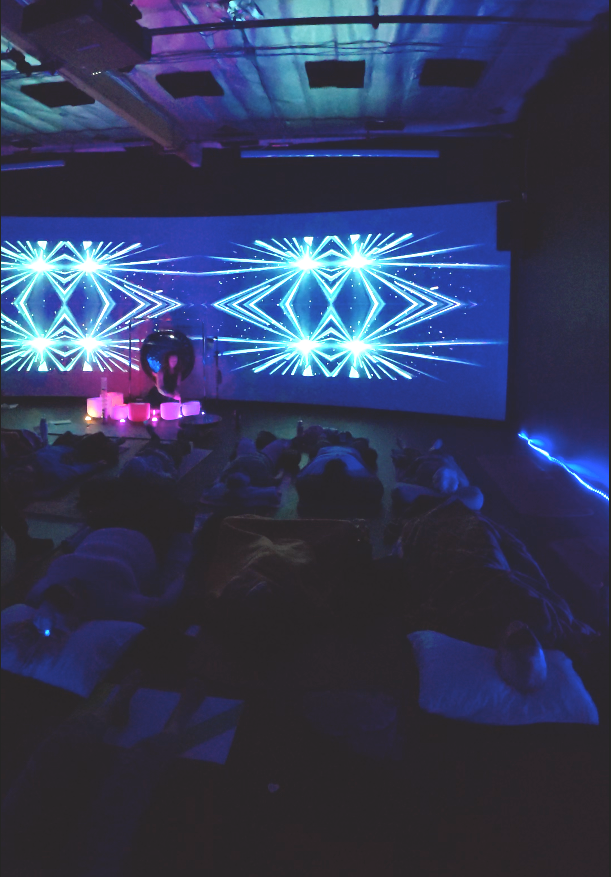 A sound bath happening with a screen backdrop with cool visuals