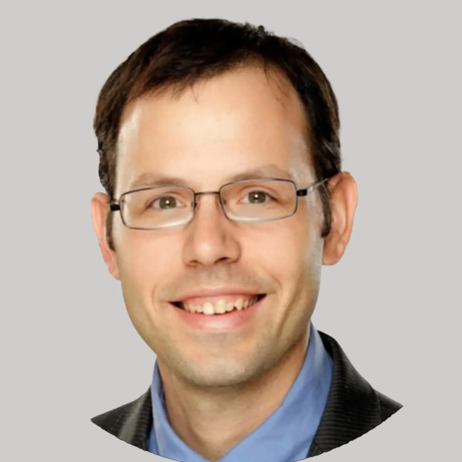 Portrait of a smiling man with glasses, wearing a dark blazer and blue shirt, set against a plain background.