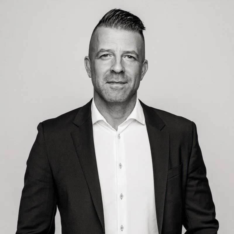 Black and white portrait of a man in a suit with a confident expression.