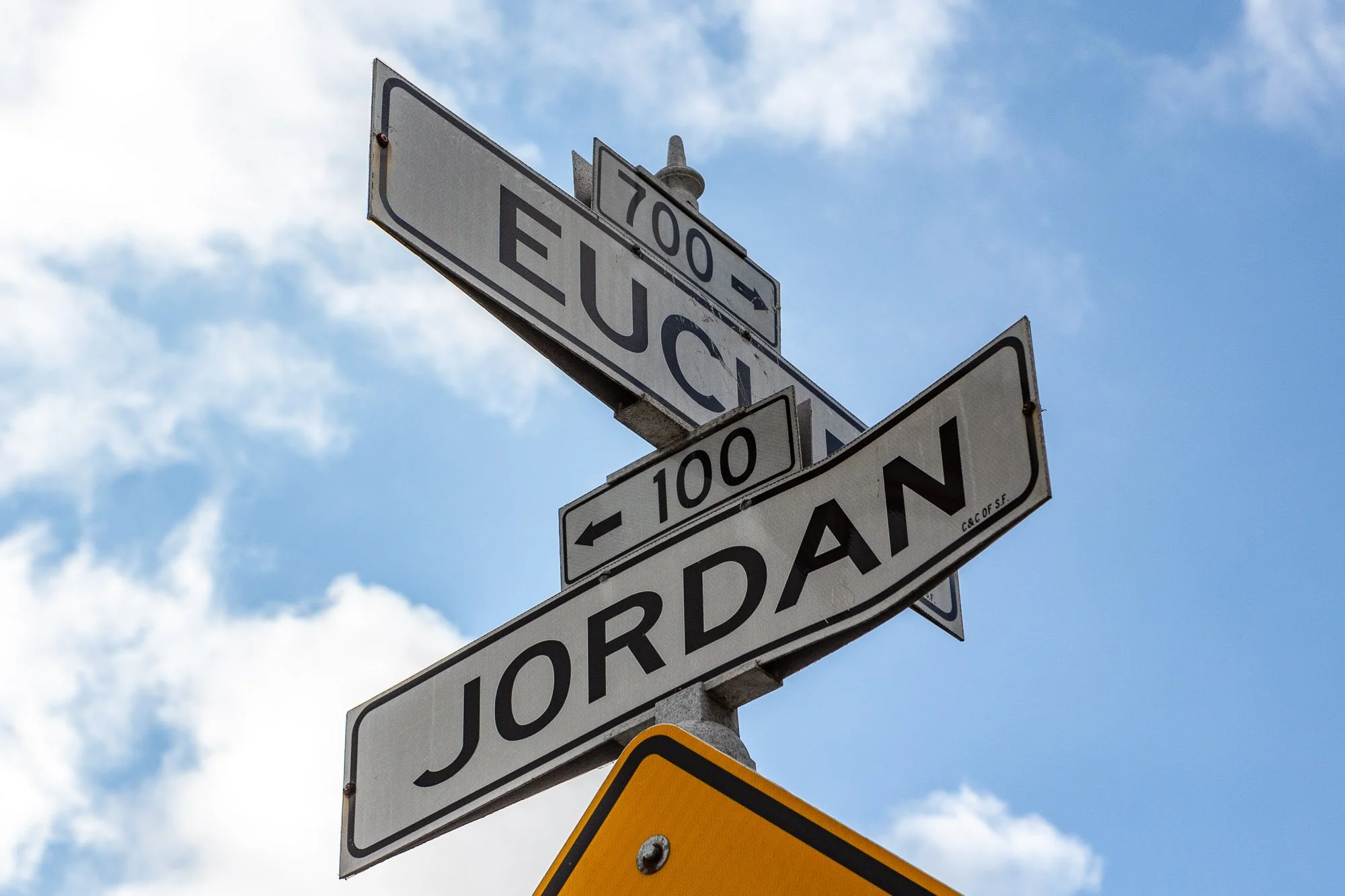 Intersection signs for Euclid and Jordan streets against a blue sky background.