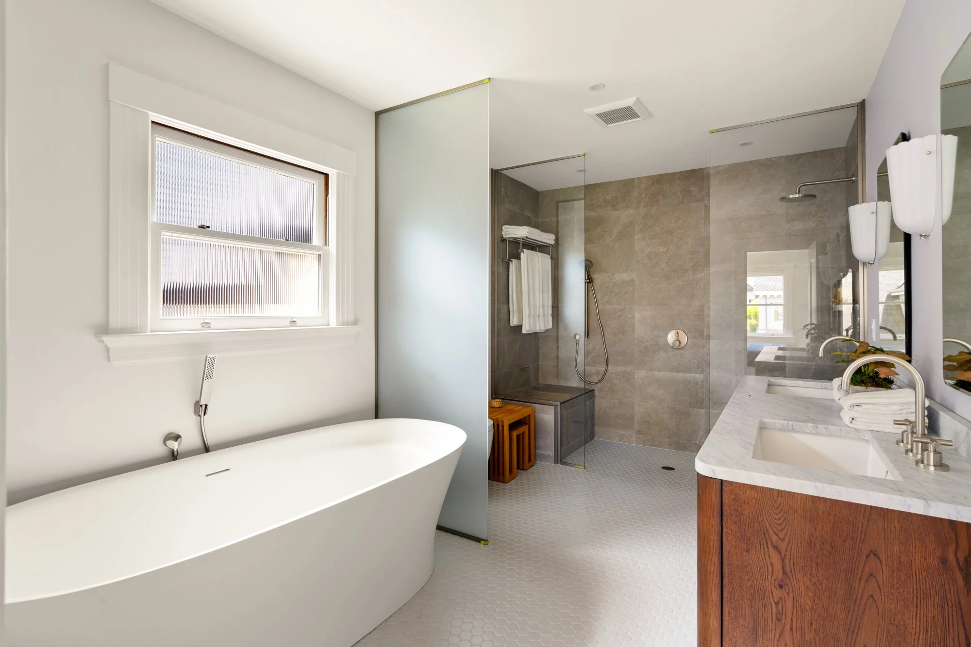 Modern bathroom with freestanding bathtub, glass shower, and double sink vanity.