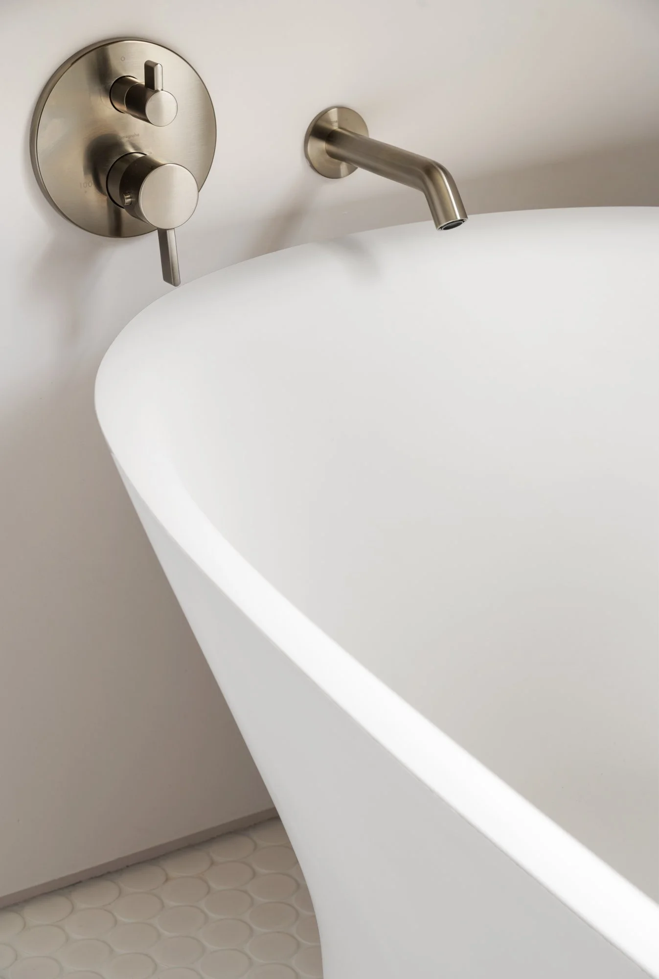 Modern bathroom with white freestanding bathtub, brushed nickel faucet, and wall-mounted controls.