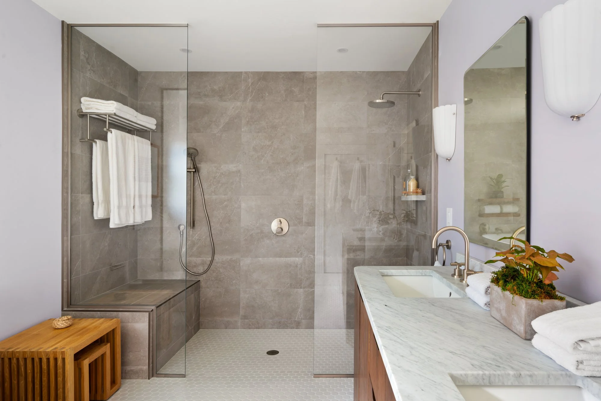 Modern bathroom with glass shower enclosure, wall-mounted showerhead, and marble countertop with dual sinks.
