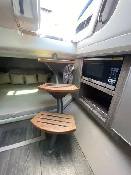Interior of a camper or RV showing a microwave, a small table, and a seating area with cushions.