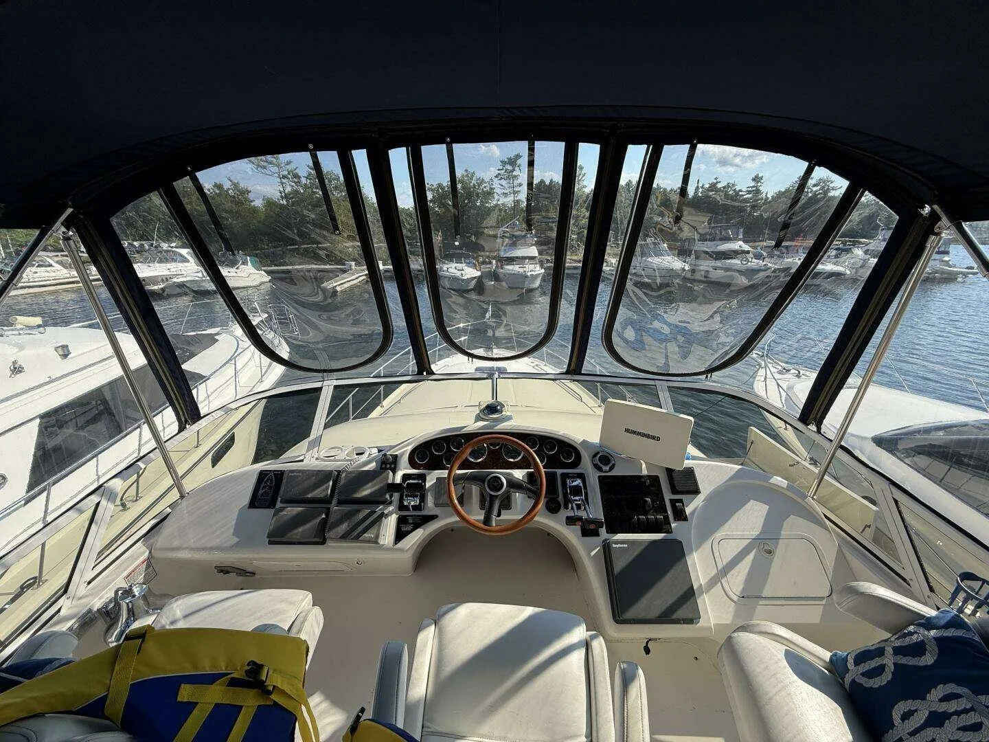 View from inside the cockpit of a boat looking out at a marina filled with boats and yachts docked on the water.