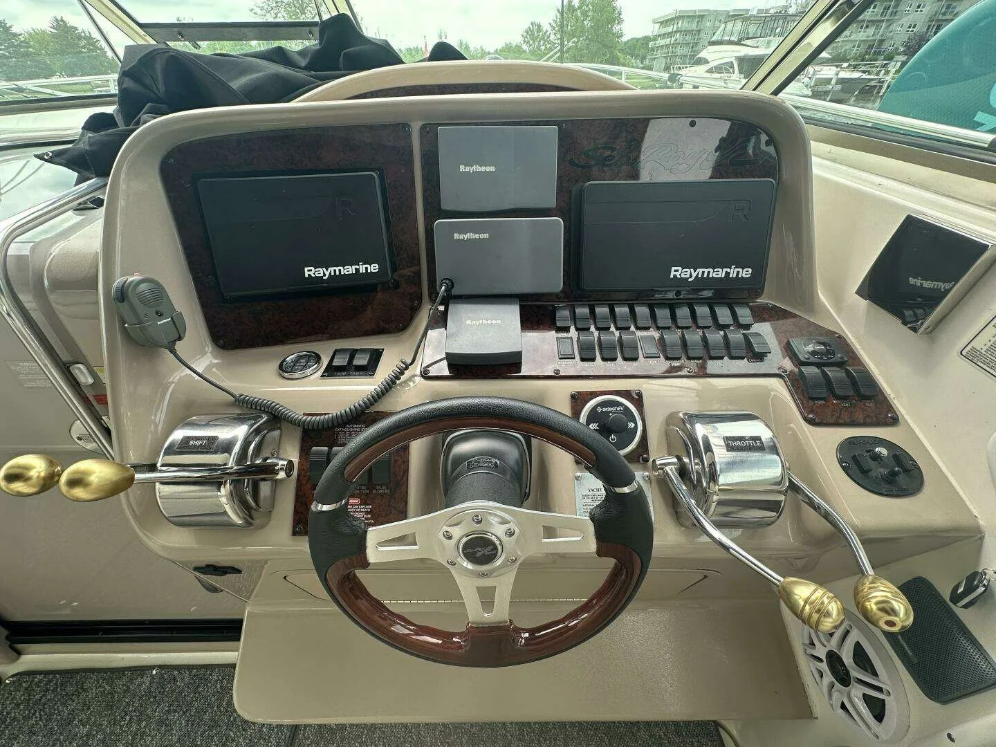 Boat helm with multiple navigation screens, throttle, steering wheel, and control switches.