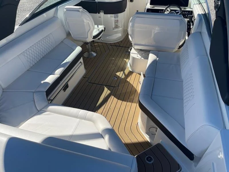 Interior of a boat with white cushioned seating, synthetic flooring, and a steering wheel at the front. Sea Ray 280 SLX.