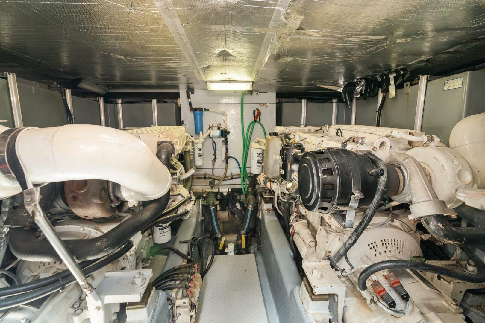 View of a marine engine room with various engines, pipes, filters, and wiring. Cummins diesel engines on a Sea Ray Motor Yacht.