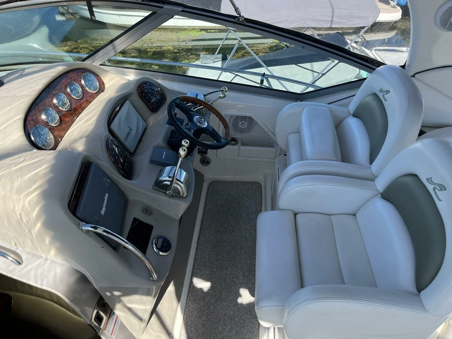 Helm on Sea Ray 340 Sundancer, with white leather seating, wooden steering wheel, and dashboard with multiple gauges and electronic displays.