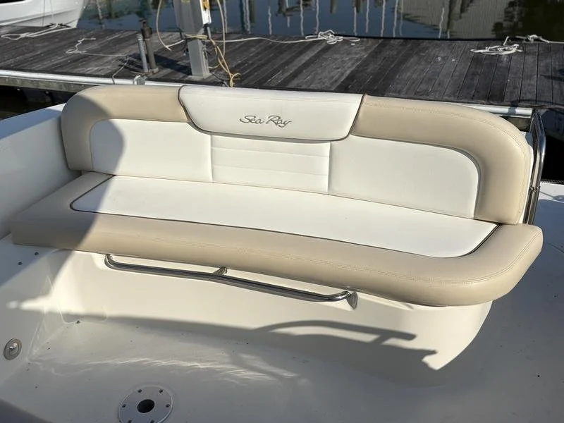 White cushioned seat with the words 'Sea Ray' embroidered on the backrest, located on a boat docked at a marina. Sea Ray 350 Sundancer.