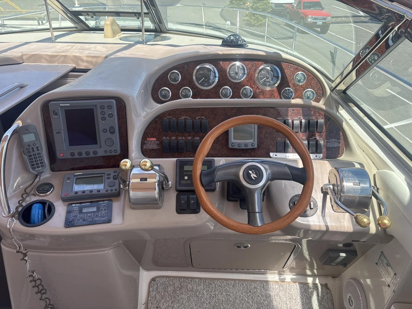 The image shows the dashboard of a Sea Ray boat, with various gauges, GPS, radio, throttle controls, steering wheel, and other navigational equipment.