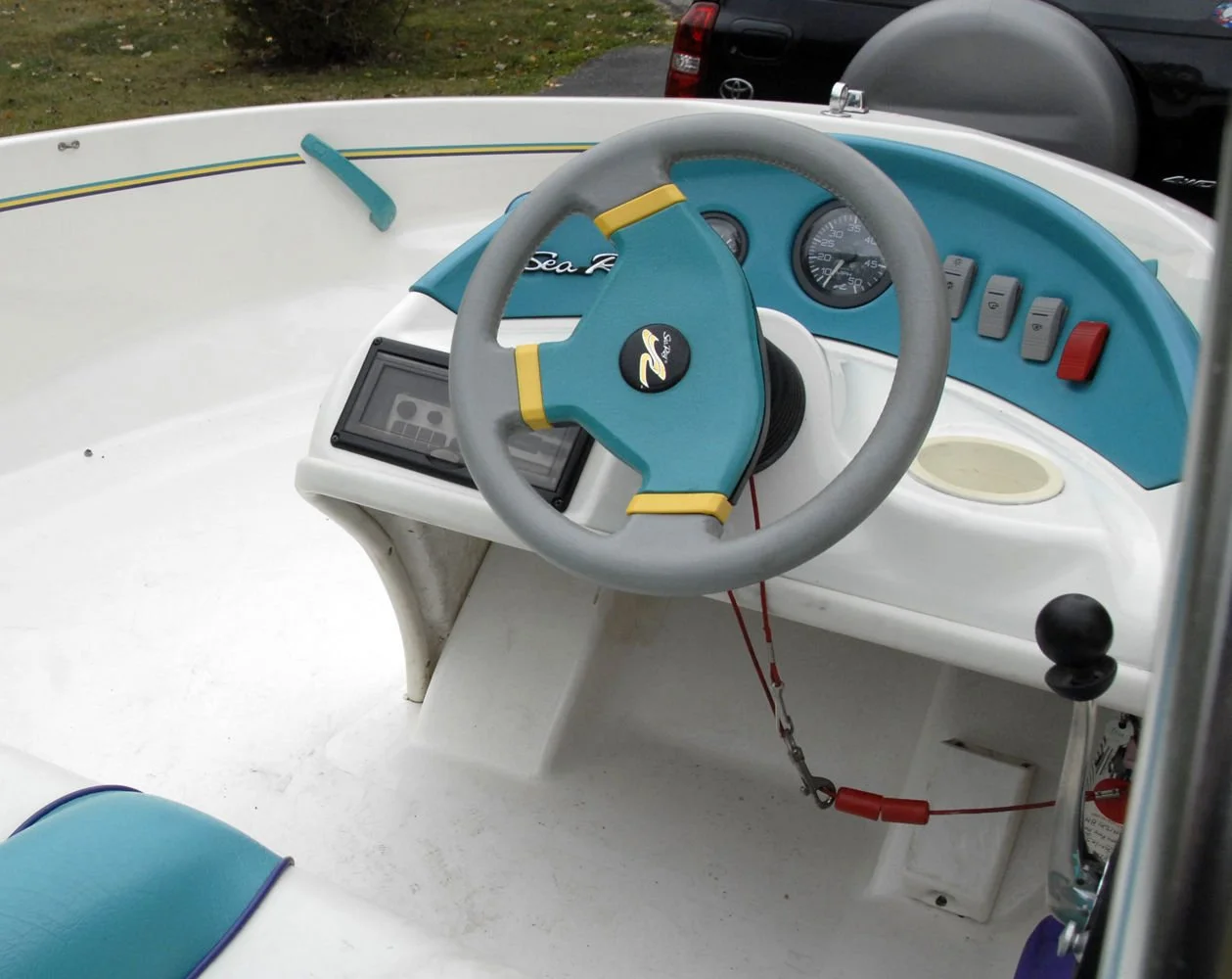 Interior of a small white and blue pedal boat with a steering wheel, control panel, and dashboard gauges.