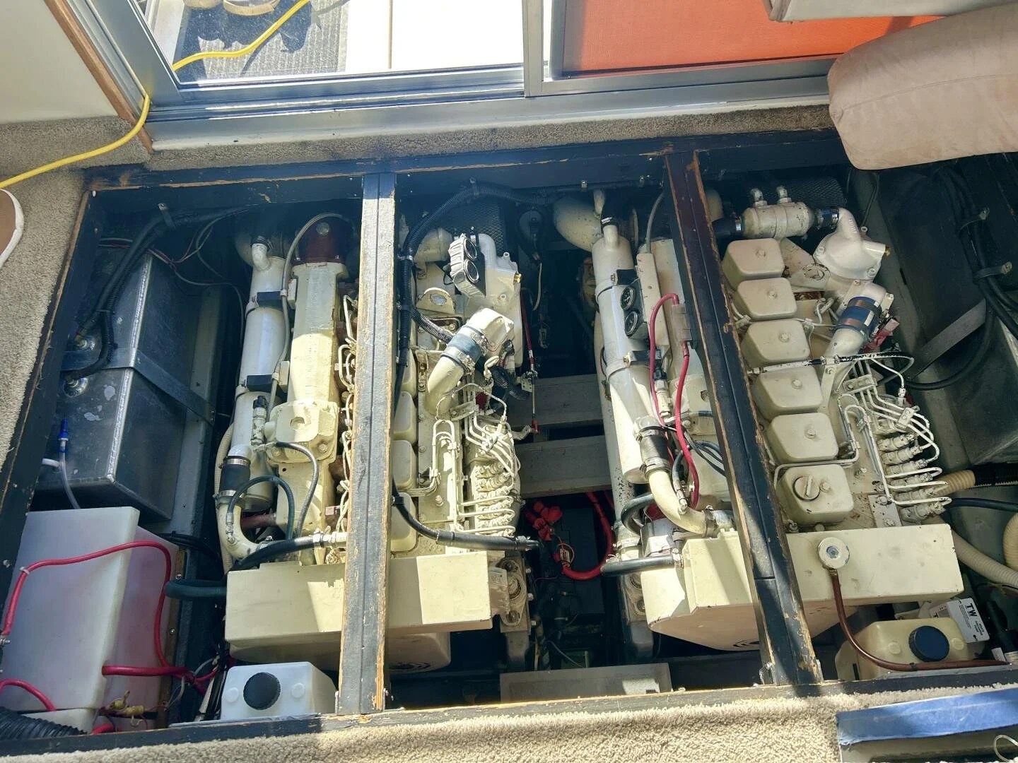 View of boat engine compartments with three vintage diesel engines and various mechanical parts.