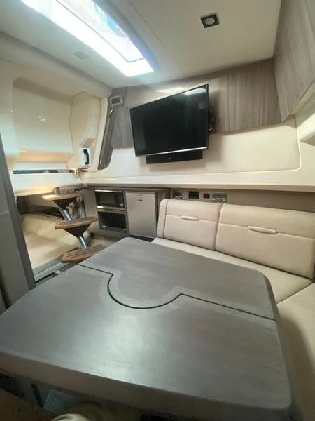 Interior of a modern camper or RV with a flat-screen TV, a beige sofa, and a table.