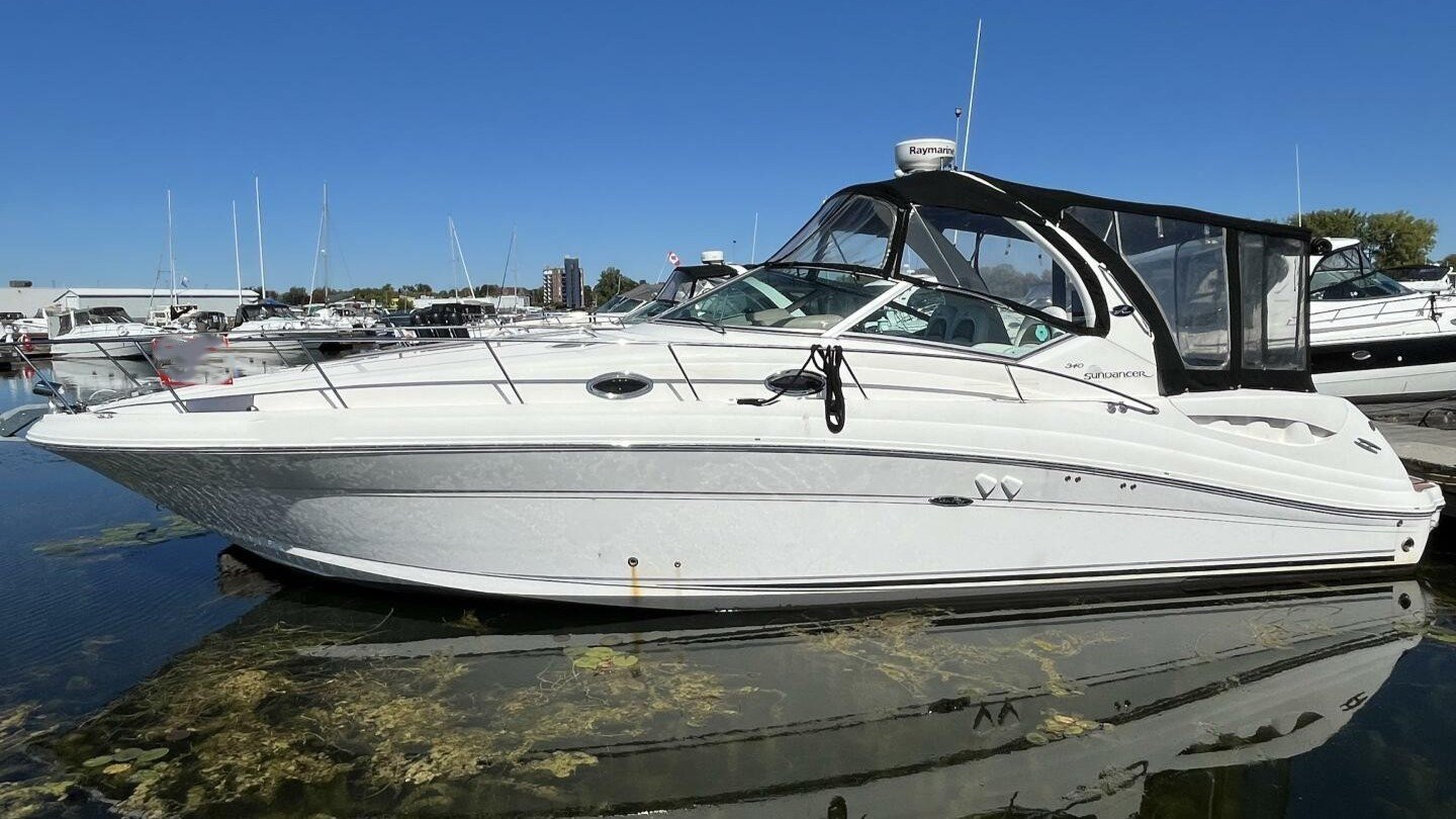 White Sea Ray 340 Sundancer yacht docked at a marina with other boats, a sunny summer afternoon, and a clear blue sky in the background.