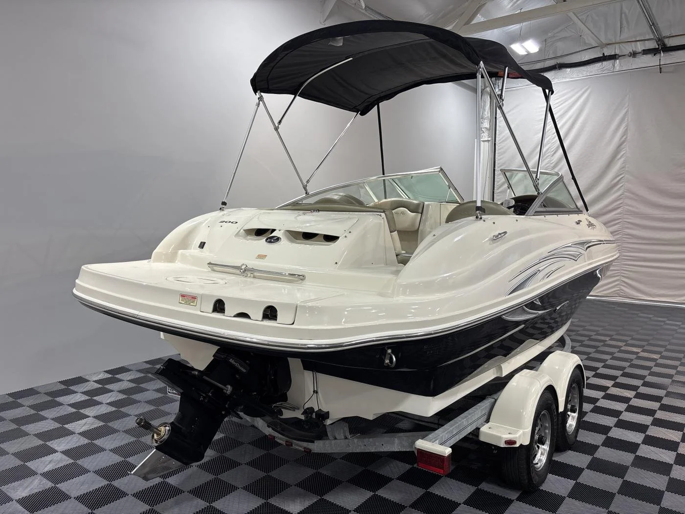 A white and black speedboat on a trailer inside a warehouse or showroom. Sea Ray boats.