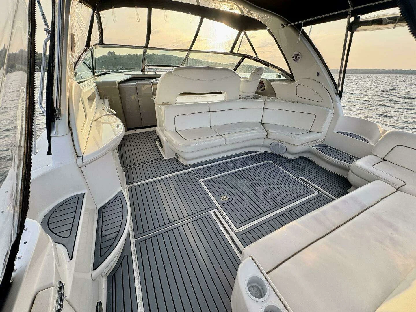 Cockpit view on a luxury Sea Ray yacht, with white seating and a view of the water and a sunset through the windows. 460 Sundancer.