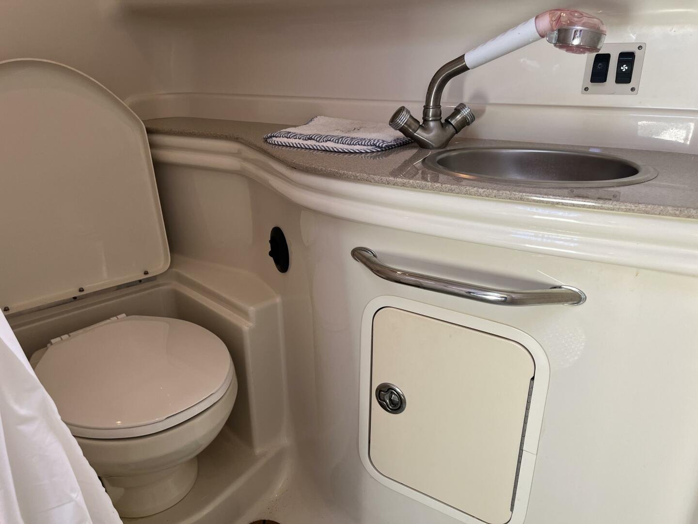Washroom and head on board Sea Ray 340 Sundancer, with toilet, small sink, faucet, and cabinet. Vacuflush toilet.