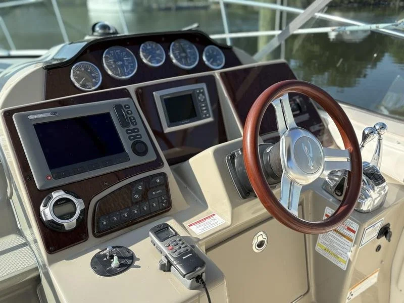 Boat cockpit with navigation and control instruments including a steering wheel, GPS or fish finder display, gauges, and throttle controls. Sea Ray 350 Sundancer.