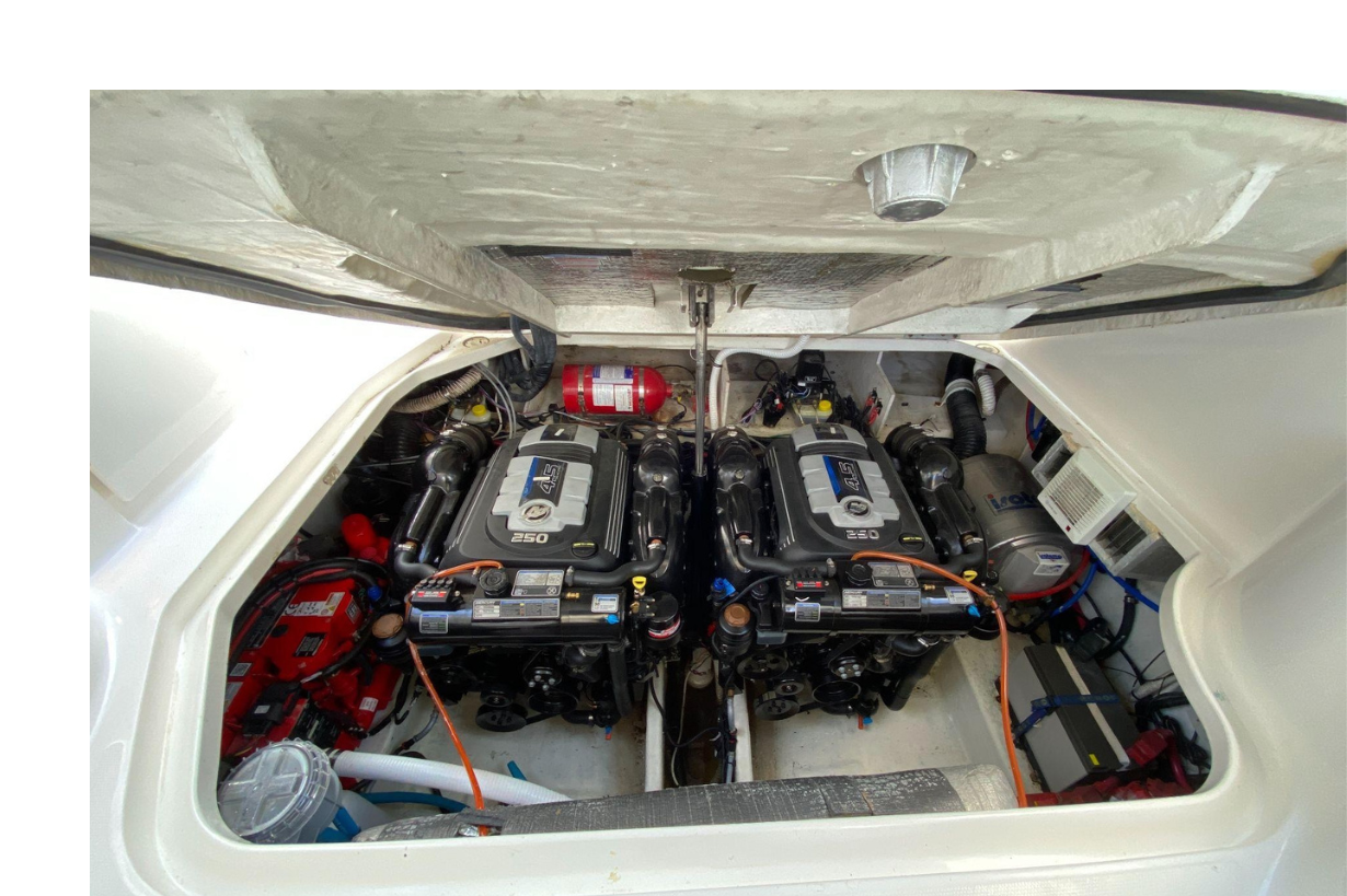 Two large marine engines with black covers labeled '4.5' and '250' in a boat engine compartment, with various wires, pipes, and parts surrounding them. Sea Ray.