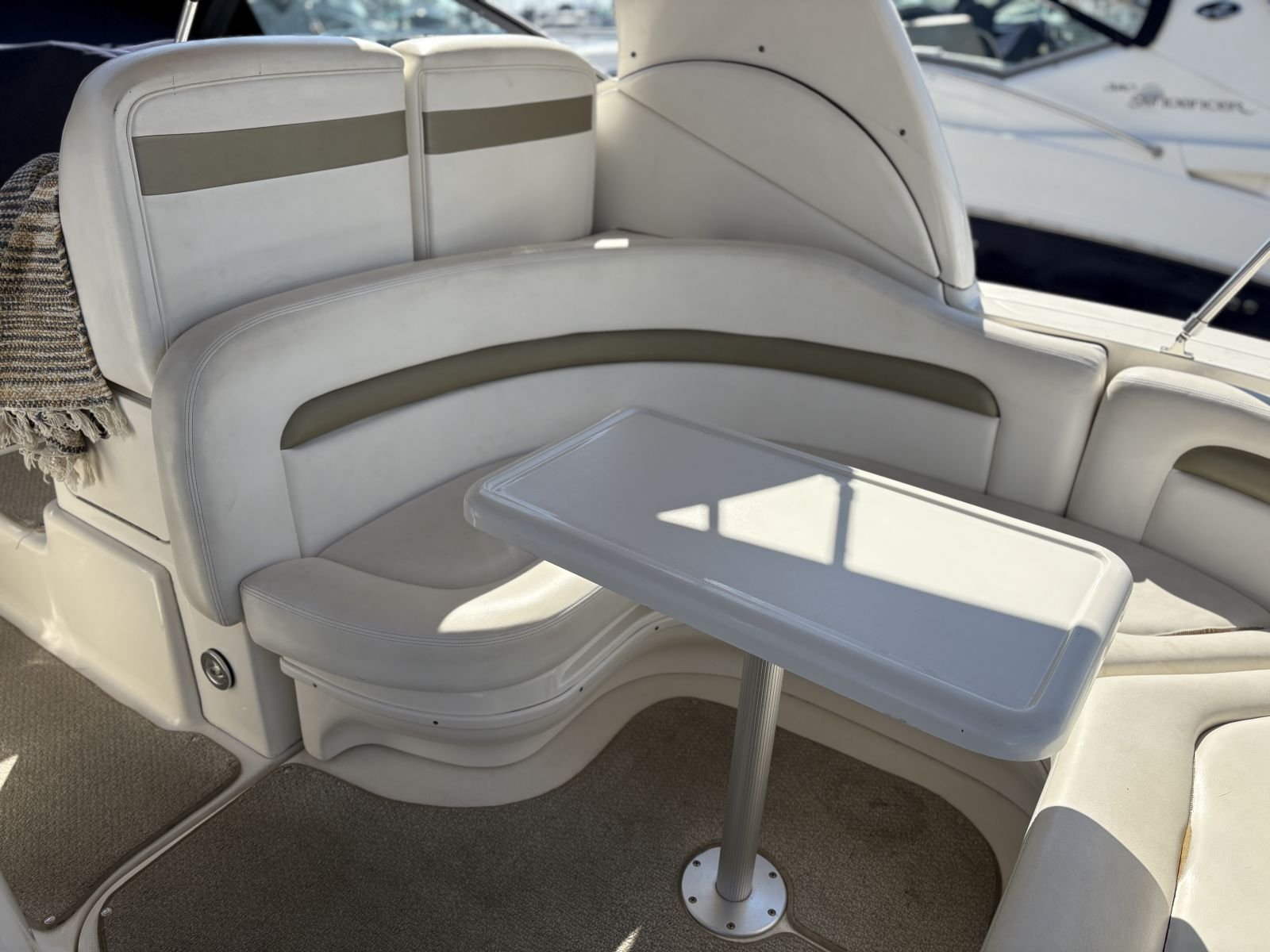 White boat seating with cushioned benches and a small table on a boat.