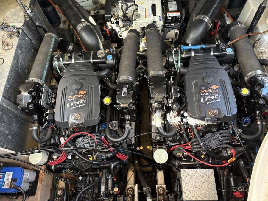 A boat engine with two black engine covers labeled 'Mercruiser 380 MPI HORIZON,' surrounded by various hoses, wires, and mechanical components. Sea Ray.