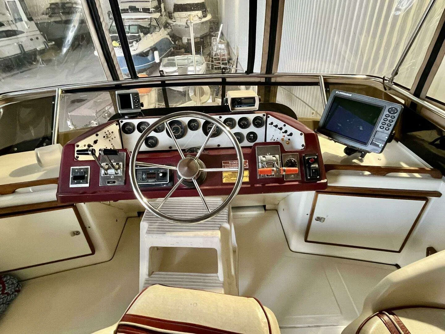 Boat cockpit with steering wheel, dashboard instruments, electronic displays, and navigation equipment.