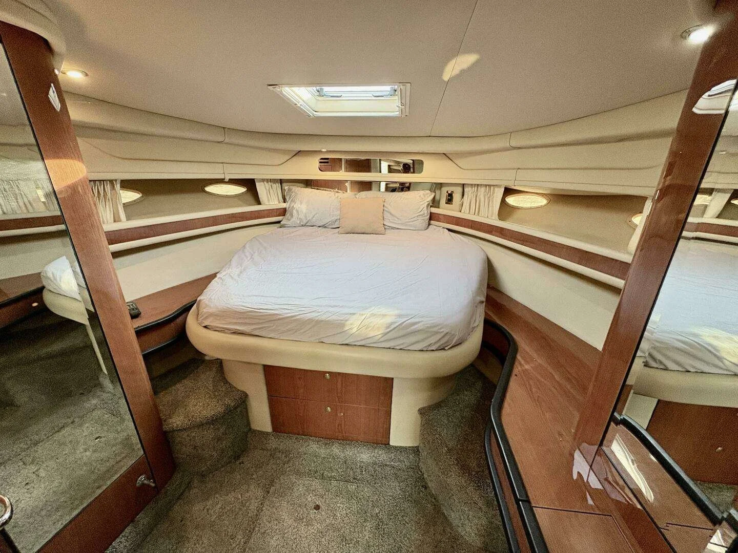 Interior on yacht, showing forward vee-berth sleeping area, a large bed, cherry wood storage cabinets. Sea Ray 460 Sundancer.