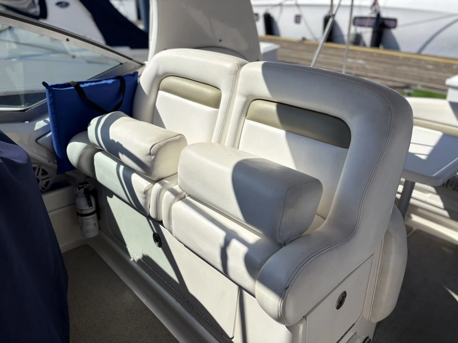 White boat seating with padded armrests and headrests, located on a boat docked near other boats.