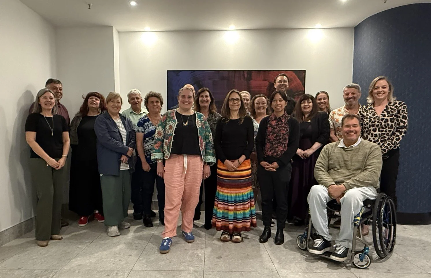 A large group stand and sit smiling at the camera