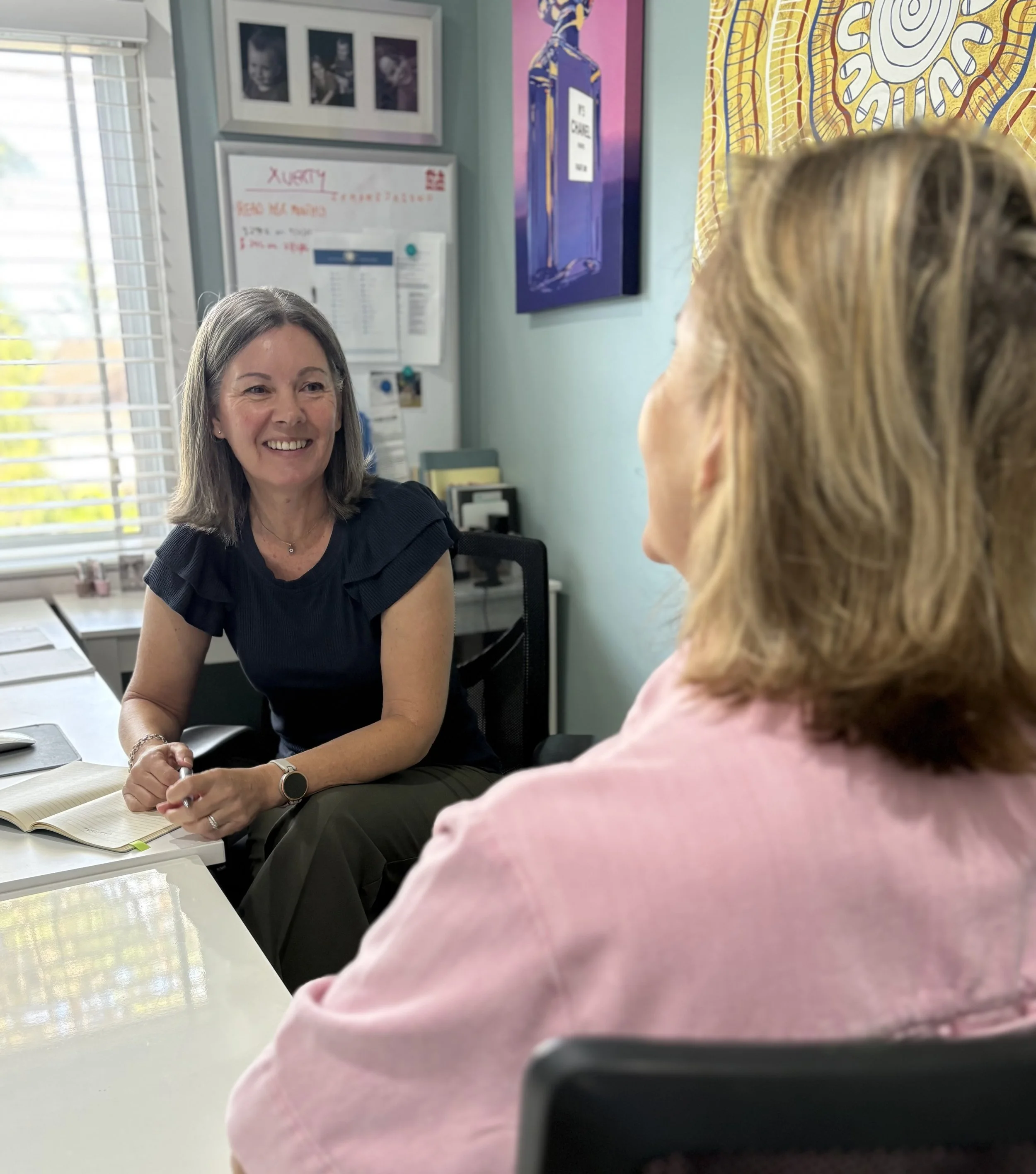 Two women sit facing each other, discussing executive coaching and facilitation
