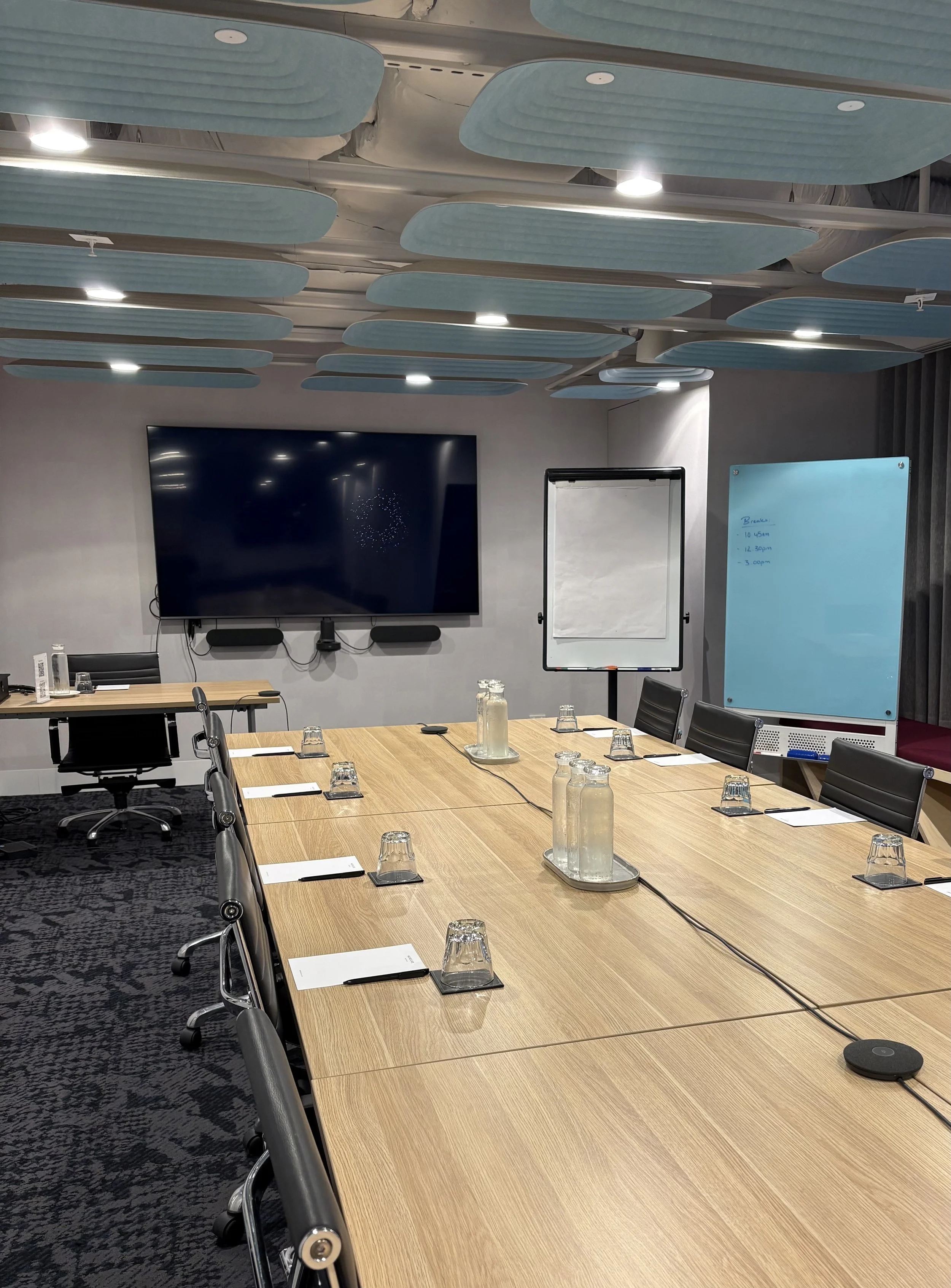 Image of a board room and multiple screens set up ready for participants