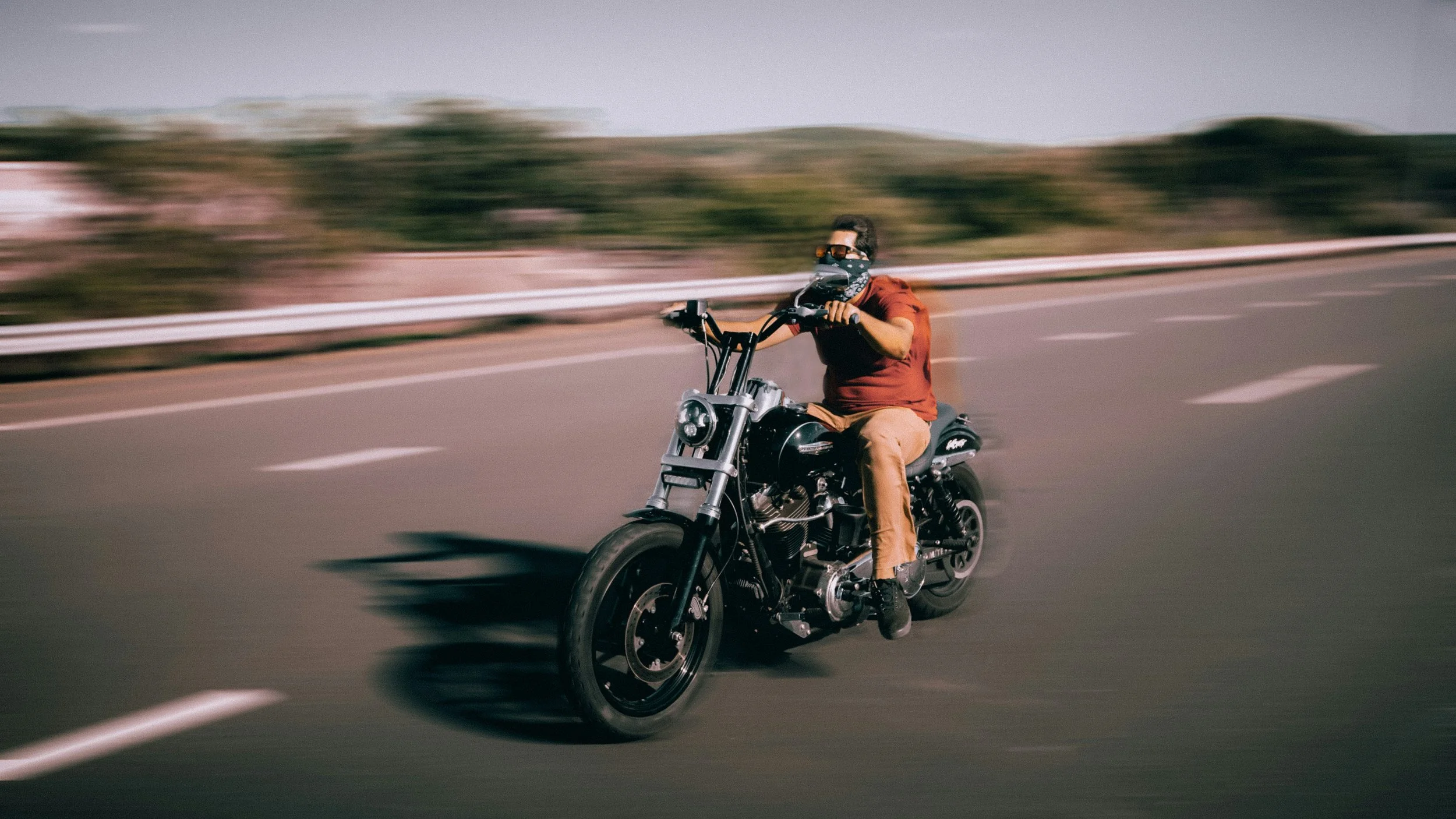 Man riding black Harley-Davidson with blurred surroundings