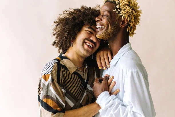 A happy couple with curly hair sharing a joyful moment, smiling and holding each other.
