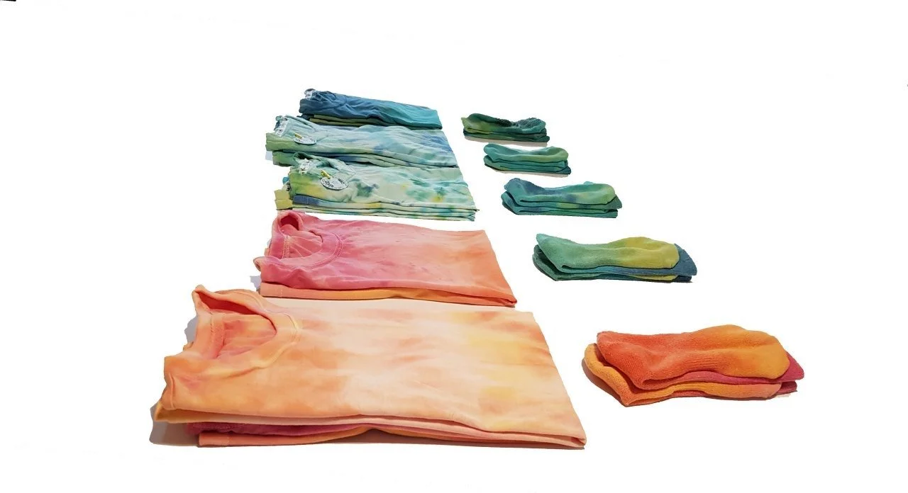 Colorful tie-dyed t-shirts and socks neatly folded and arranged on a white background.