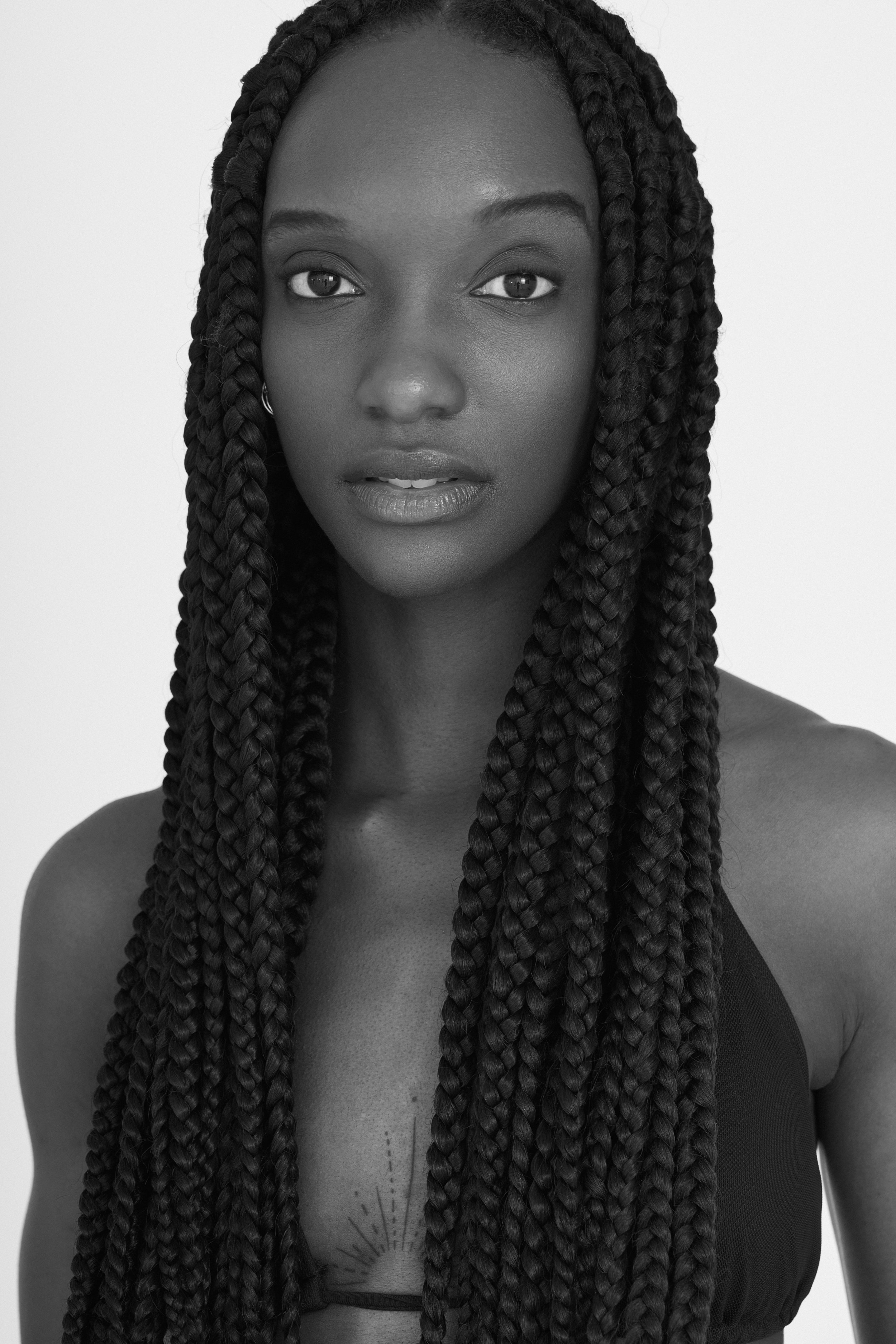 Retrato en blanco y negro de una mujer con trenzas largas y rizadas, con expresión serena y mirada directa.