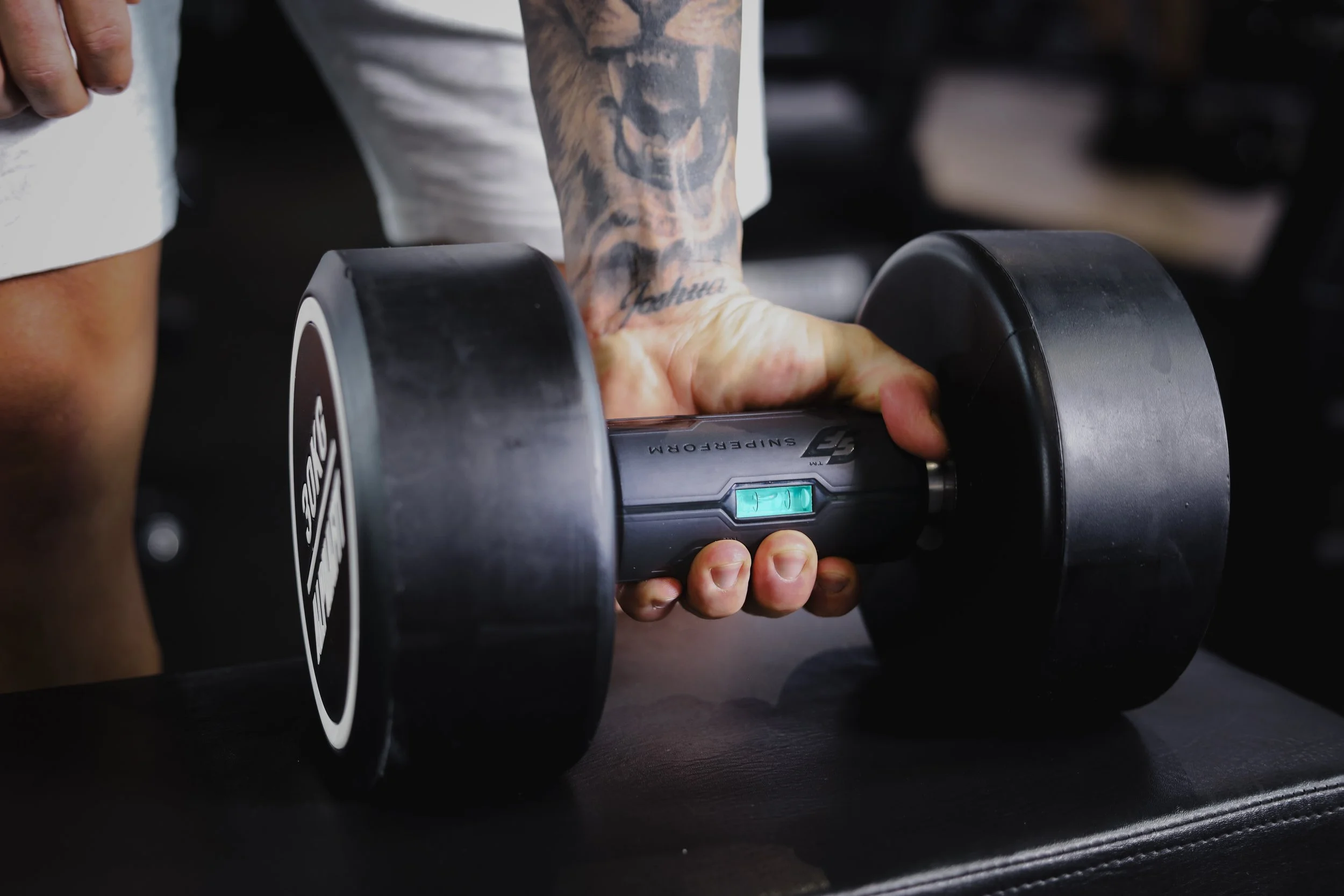 Close-up of a tattooed arm pressing buttons on a black and silver electronic weight scale.